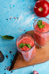  classic spanish raw eating cold soup Gazpacho served  in glasses around blue background. food recipe. healthy concept.