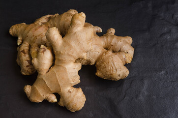 Fresh organic ginger on black stone background