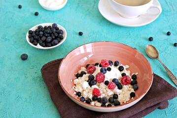 Breakfast, fresh organic farm cottage cheese with sour cream and berries, fresh blueberries and frozen raspberries. Healthy food.