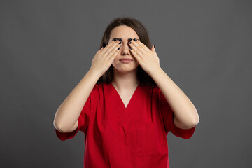 Portrait of attractive female nurse covering eyes like blind gesture