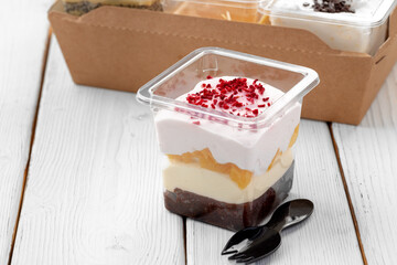 Creamy dessert in a plastic box on wooden table