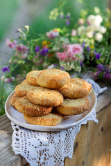 Shortbread cookies with blue cheese and sesame seeds and a wreath of wildflowers on a summer terrace. Rustic style.