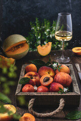 Rustic summer fruits harvesting, box with peaches and apricots, orange melon