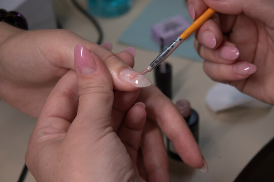 the process of doing manicure. Closeup of hands of professional manicurist, applying nail polish. Concept of doing manicure and fingernails cleaning. beauty concept. Gel polish, shellac