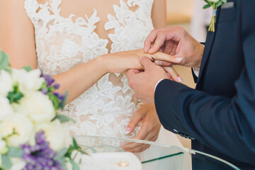 Obraz na płótnie Canvas Groom puts ring on bride at wedding registration