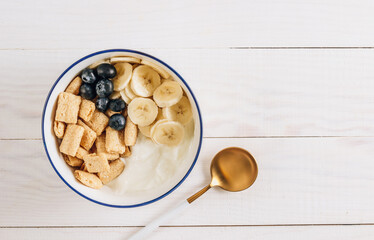 Bowl with amaranth corn pads with banana, blueberry and yogurt on white wooden background. Healthy breakfast and gluten free concept. Top view with copy space. Flat lay