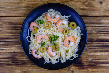 Italian pasta with shrimps and olives in a black plate. Top view