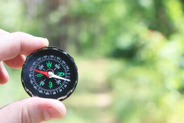 Old classic navigation compass in hand on natural background as symbol of tourism with compass,...