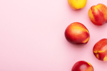Bright juicy ripe nectarines peaches on a pink background top view. Food organic background. Summer fruits, food for a healthy lifestyle flat lay, copy space.