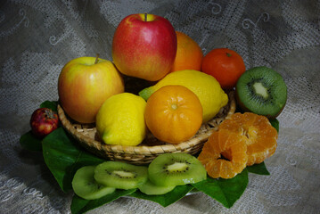A basket with colorful seasonal fruit: lemon, mandarin, apple, pomegranate, orange, kiwi