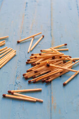 Wooden matches lying on a blue table, one match burns