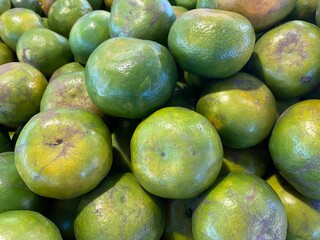pile of green orange tangerine at the market in Thailand