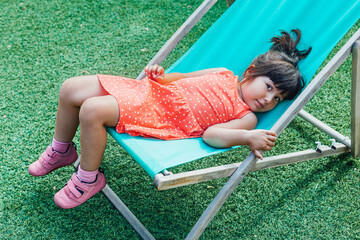 A black-haired girl lying on a lounger in the garden in summer
