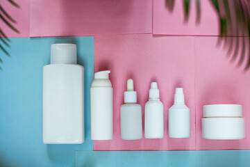 Simple Blank white Plastic Bottles Set.set of cosmetic products on a pink blue background. Cosmetic package collection for cream, soups, foams, shampoo.Mock up white cosmetic bottles with palm leaf.