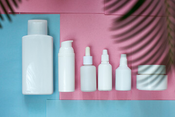 Simple Blank white Plastic Bottles Set.set of cosmetic products on a pink blue background. Cosmetic package collection for cream, soups, foams, shampoo.Mock up white cosmetic bottles with palm leaf.