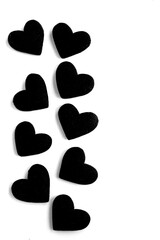 Fototapeta na wymiar Black hearts on the white background. Copy space. Top view. Location vertical.