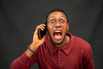 young black man feeling excited while making a phone call, feeling surprised © Confidence