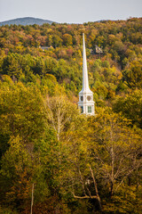 The steeple of the Stowe Community Church, Stowe, VT.  The church Steeple is surrounded by trees with autumn colored leaves