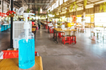 Blue alcohol gel bottle on table for customers to clean their hands before entering the food court to prevent the spread of Corona virus(Covid-19).New normal lifestyle.Trends of supporting business