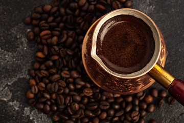 Fototapeta premium Coffee beans and turk on dark surface