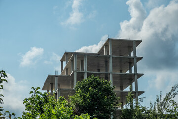 Frame of a monolithic house. Reinforced concrete structures of floors and columns. Incomplete construction of a high-rise building. Apartments under construction against the blue sky. Summer. Day. Geo