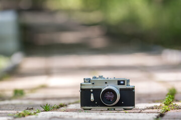 Spring time mood still life: vintage rangefinder camera laying on pavement with leaves of grass...