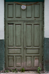 Old abandoned green wooden entrance door with a round lantern.