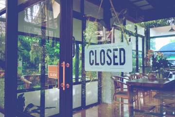 Text Closed door sign and hanging up on glass door of coffee shop .