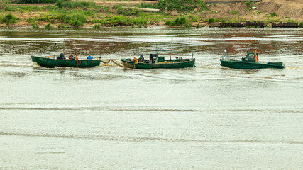 Obraz premium three fishing boats are sailing along the coast