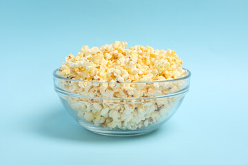 Bowl with popcorn on blue background. Food for watching cinema