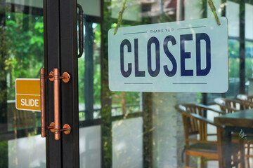 Text Closed door sign and hanging up on glass door of coffee shop .