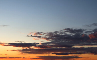 Blue evening sky with low clouds of dark blue and orange clouds in summer.