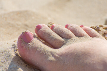 Toes of a girl who is sunbathing on the beach on a sunny day. Holidays at sea. Pedicure for swimming in the sea.