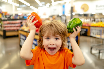 Fototapeta premium Cute toddler boy in a food store or a supermarket choosing fresh organic carrots. Healthy lifestyle for young family with kids