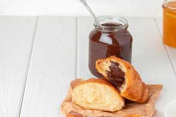 Fresh croissants with berry jam on dark wooden board