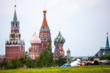Fototapeta na wymiar A couple rests on the grass against the background of the Kremlin
