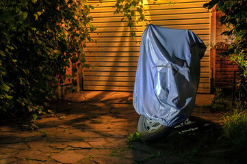 Motorcycle in waterproof sunshade tent  standing by the garage gate in the night.