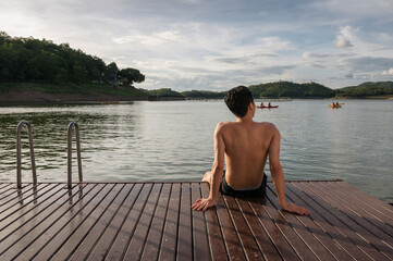 Young asian man relaxing on lakeside