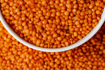 White ceramic bowl of red lentils on wooden table