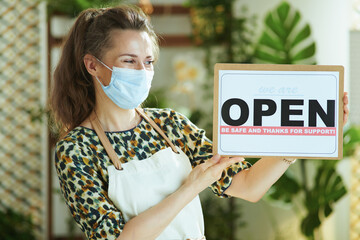 stylish business owner woman in apron showing welcome sign