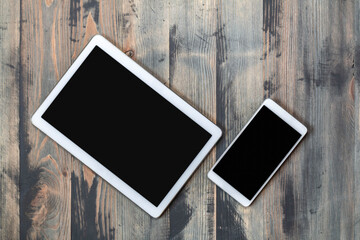 Smartphone and tablet on wooden vintage background top view