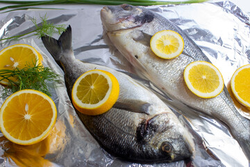 Two fresh dorada fish with lemon and dill on top