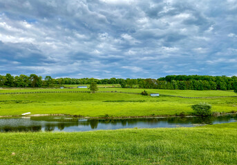 Countryside Landscape with Green Fields, Cloudy Sky and Stream