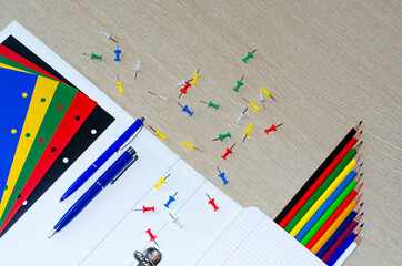 Colorful composition of vibrant color school supplies: colored pencils, papers, pens on the withe wooden background. Copy space. Flat lay. Back to school and office concept.