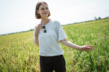 a woman poses in the middle of a rice field with exotic view in the bright sunny day