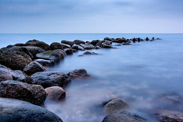 Breakwater Stones in the ocean dark mood for postcards about grief mourning or peaceful and soothing meditation and relaxation
