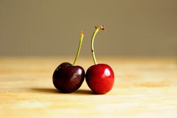 Close up of two cherries on the wooden table