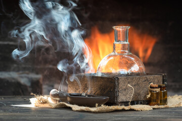 Magic potion on the table on burning fire in fireplace background. Alchemy concept.