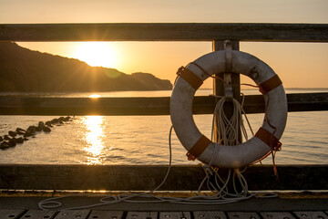 lifebuoy on harbor railing at sunset