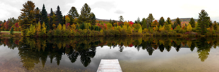 A panoramic view of a small pond during the fall season.